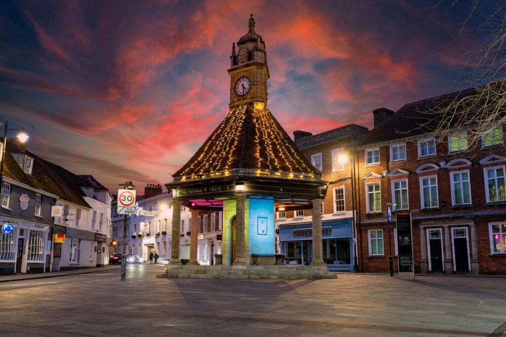 A beautifully lit historic clock tower in Newbury, England, at sunset with dramatic skies.