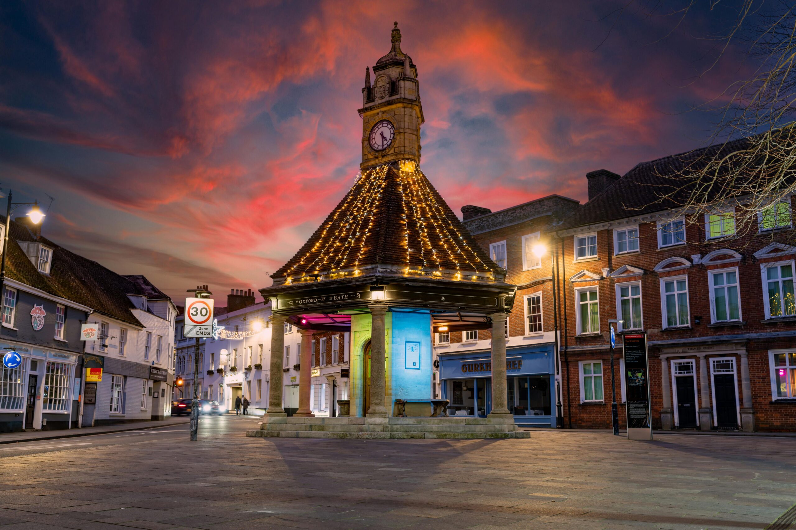 A beautifully lit historic clock tower in Newbury, England, at sunset with dramatic skies.
